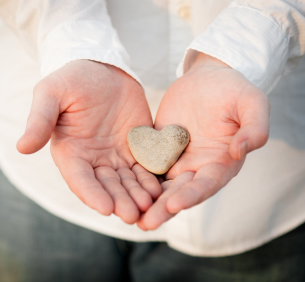 Photo of hands holding heart-shaped rock
